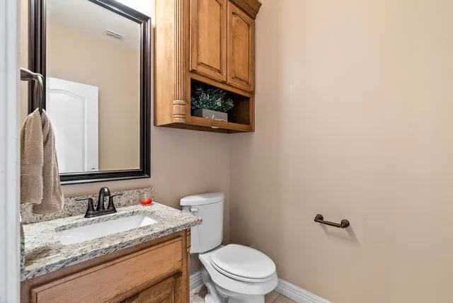 a bathroom with a granite countertop sink toilet and mirror