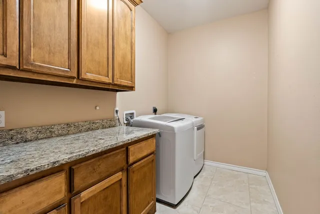 a utility room with granite countertop cabinets washer and dryer