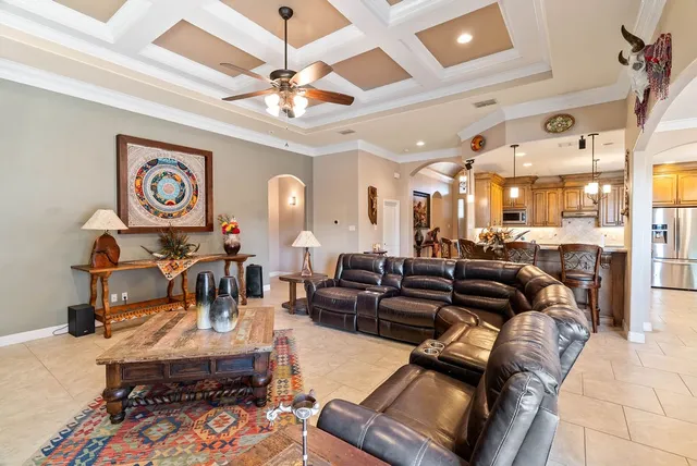 a living room with furniture kitchen view and a chandelier