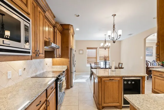 a large kitchen with kitchen island a large counter top space appliances and cabinets
