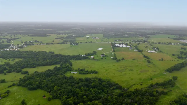 an aerial view of residential houses with outdoor space and trees
