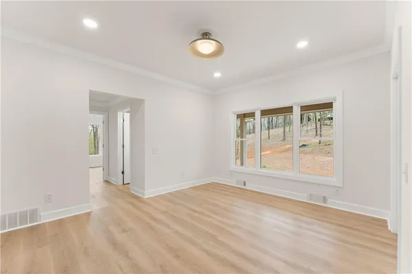 a view of an empty room with a window and wooden floor