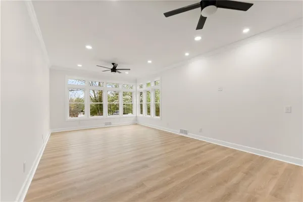 an empty room with wooden floor ceiling fan and window