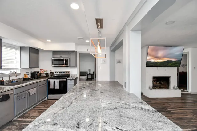 a large kitchen with stainless steel appliances granite countertop a stove top oven a sink dishwasher a dining table and chairs with wooden floor