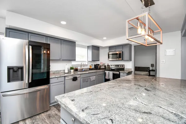 a kitchen with stainless steel appliances granite countertop a stove refrigerator sink and microwave