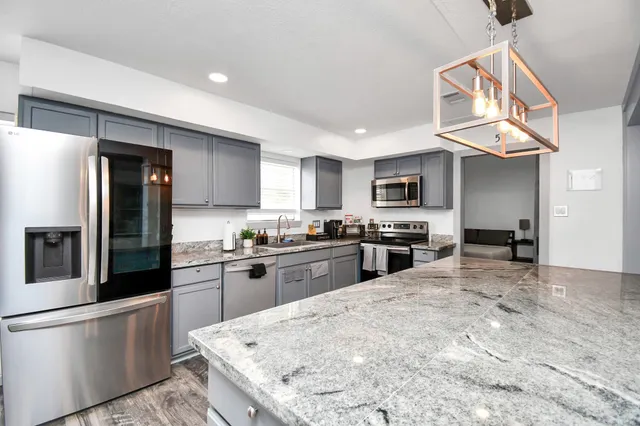 a kitchen with stainless steel appliances granite countertop a stove refrigerator sink and microwave