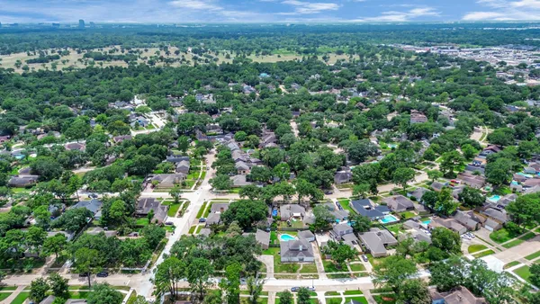 an aerial view of residential houses with outdoor space and trees