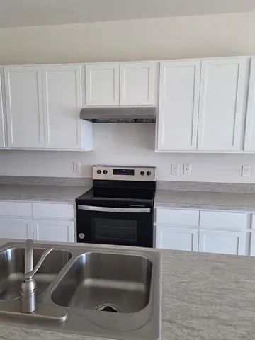 a kitchen with white cabinets and a wooden floor