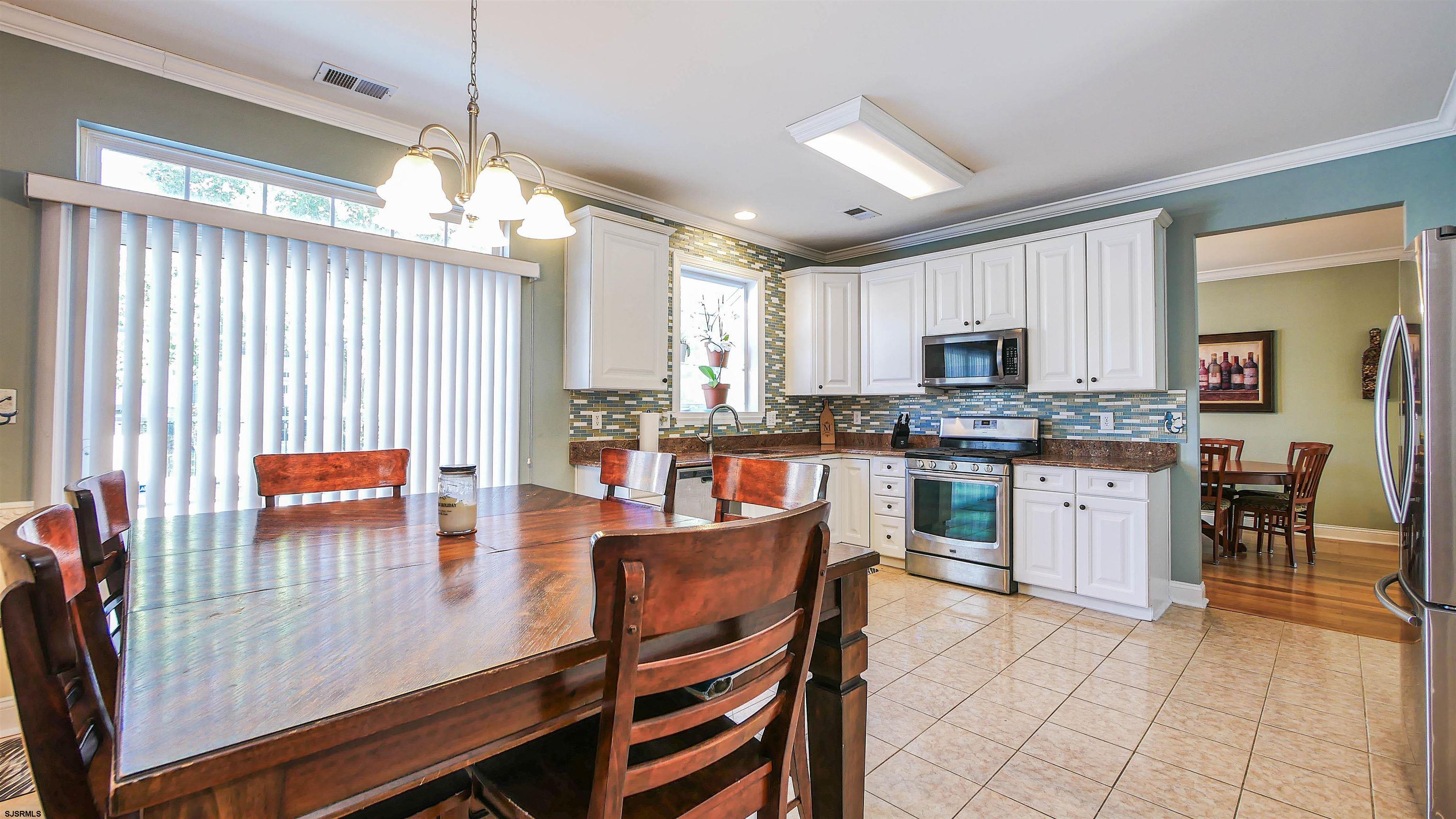 101 Haviv Drive Northfield, NJ 08225 - Photo 11 of 38 a kitchen with stainless steel appliances granite countertop a stove top oven a sink dishwasher a dining table and chairs with wooden floor