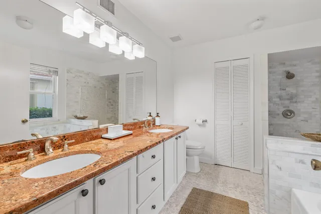a bathroom with a granite countertop double vanity sink and mirror with shower