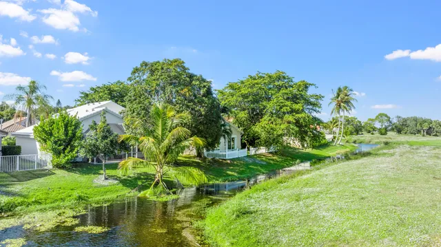 a view of a white house with a big yard and potted plants