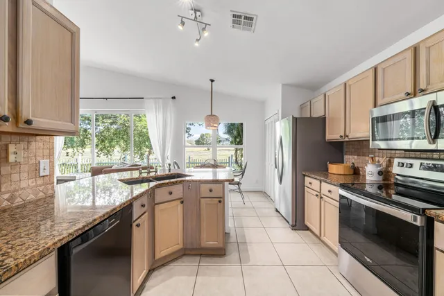 a kitchen with stainless steel appliances granite countertop a stove a sink and a refrigerator