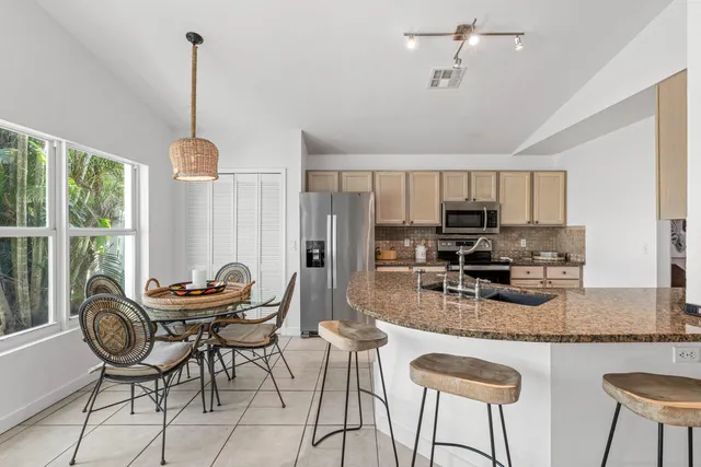 a kitchen with stainless steel appliances granite countertop a stove top oven a refrigerator a sink and chairs