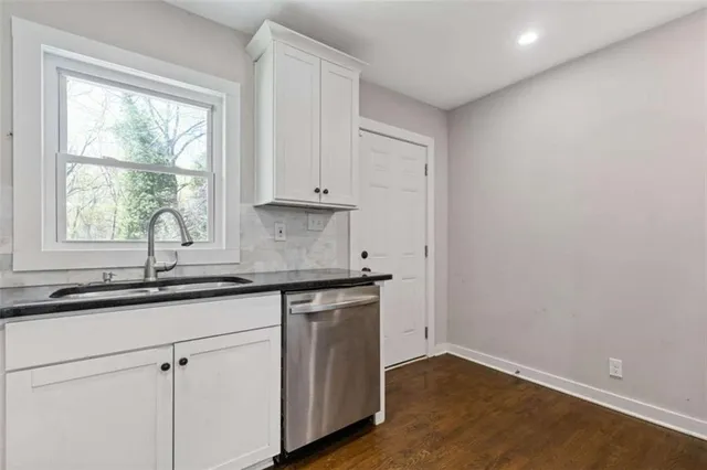 a kitchen with granite countertop white cabinets and a sink