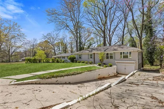 a view of a house with a yard and large trees