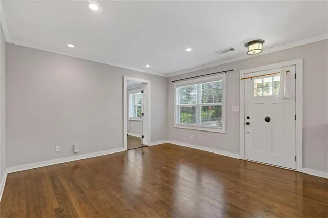 a view of an empty room with wooden floor and a window