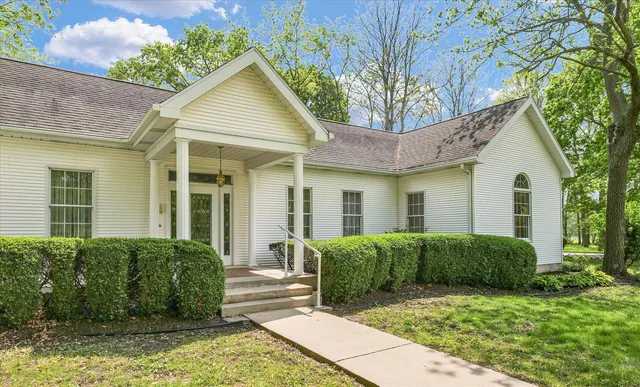 a view of a house with a small yard plants and large tree