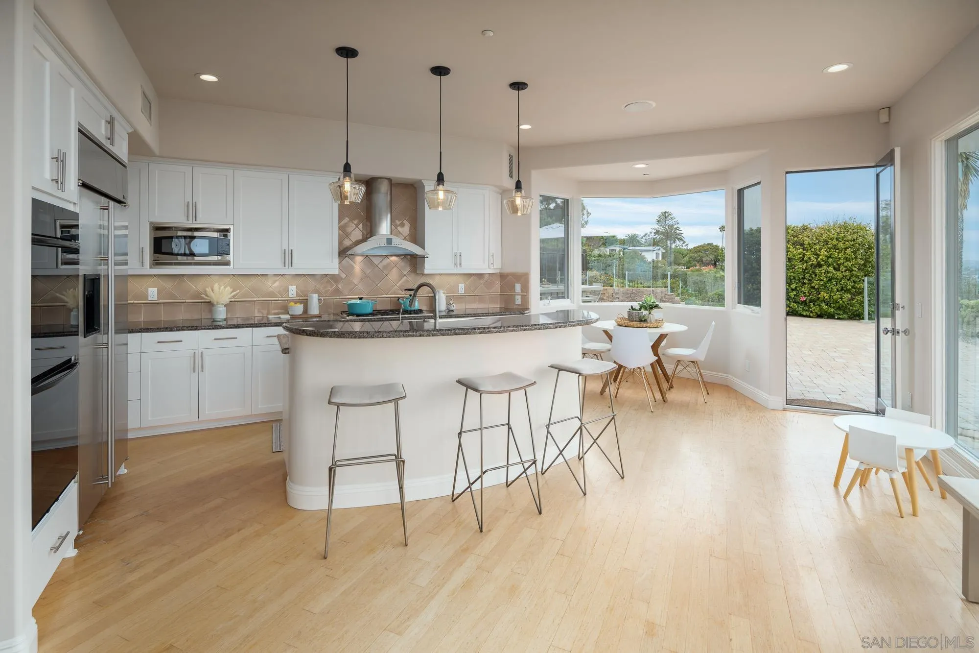1953 Crest Drive Encinitas, CA 92024 - Photo 31 of 42 a kitchen with stainless steel appliances granite countertop a stove a sink a oven a dining table and chairs with wooden floor
