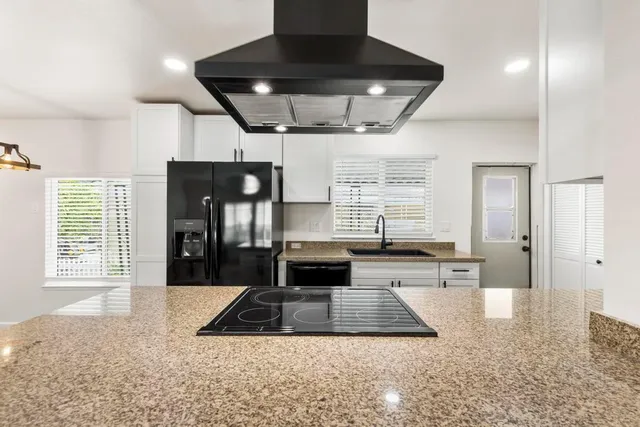 a living room with stainless steel appliances granite countertop furniture a fireplace a rug and a window