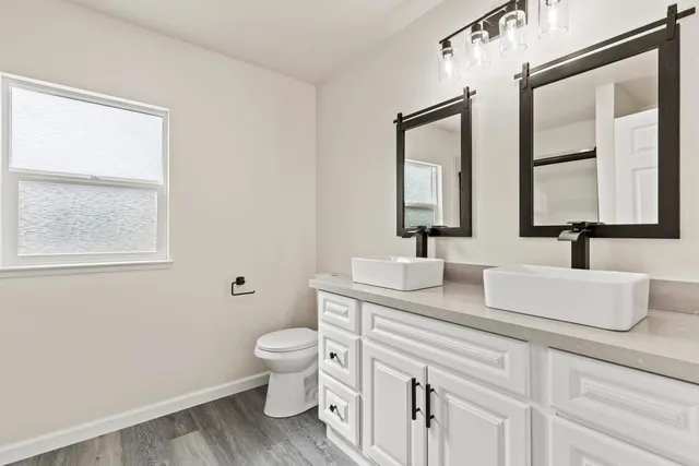 a bath room with a toilet a sink and a mirror