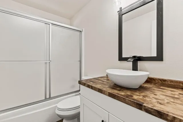 a bathroom with a granite countertop sink toilet and a mirror