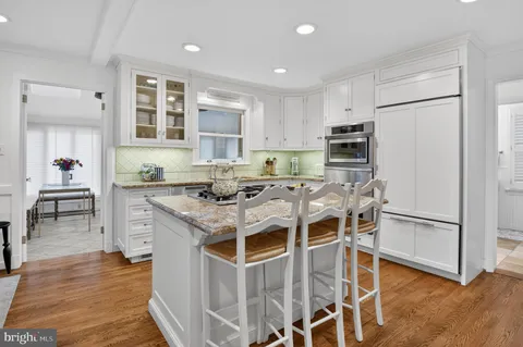 a kitchen with granite countertop cabinets a stove a sink and a dining table with wooden floor