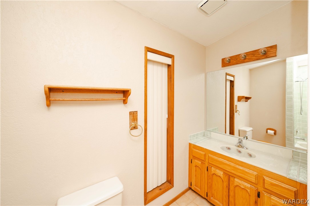 2100 East Valley View Road Kingman, AZ 86409 - Photo 25 of 53 Bathroom vanity featuring wood-finish cabinetry, a white countertop with an integrated sink, and an expansive wall-mounted mirror