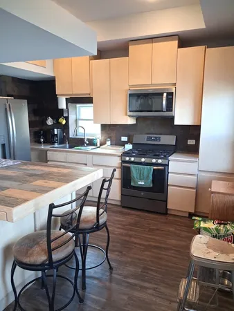 a kitchen with stainless steel appliances wooden floors wooden cabinets dining table and chair