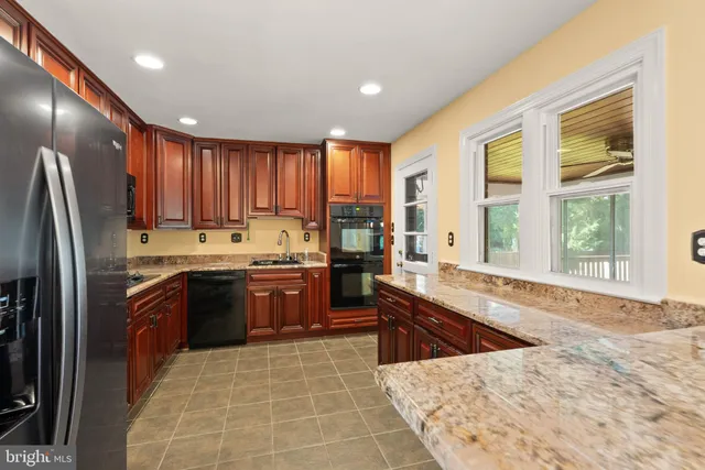 a large kitchen with kitchen island granite countertop a large window and stainless steel appliances