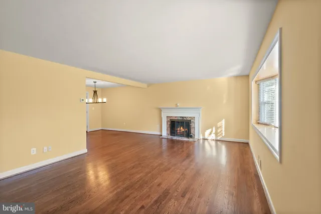 an empty room with wooden floor fireplace and windows