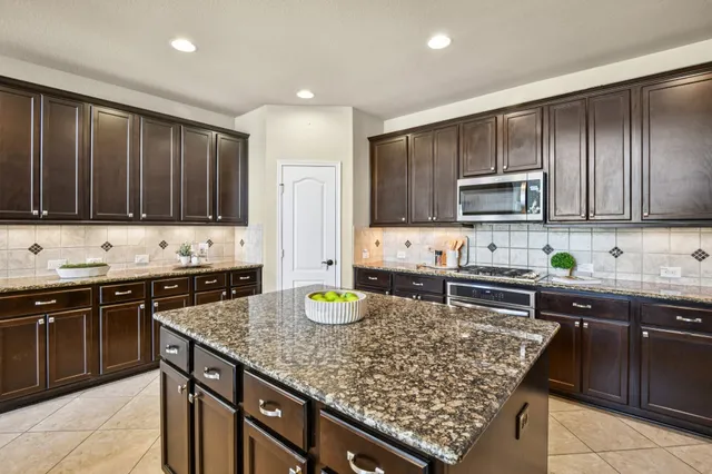 a kitchen with stainless steel appliances granite countertop wooden cabinets a sink dishwasher a stove and a refrigerator