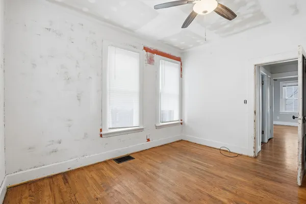 a view of an empty room with wooden floor and a window
