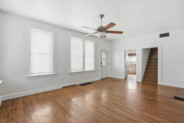 a view of an empty room with a window and wooden floor