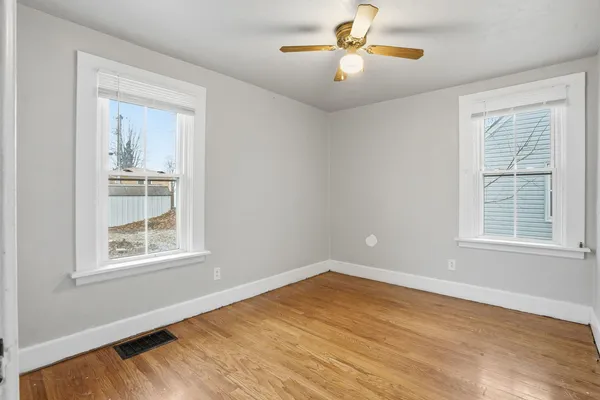 a view of an empty room with a window and wooden floor