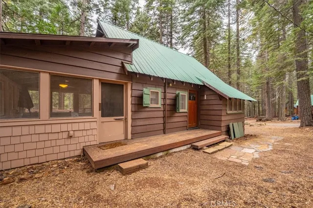 a view of wooden house with large trees