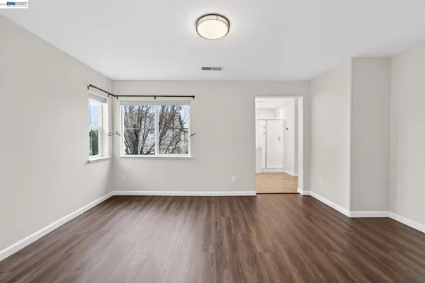 an empty room with wooden floor and windows