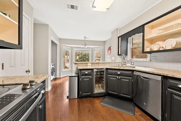 a kitchen with stainless steel appliances granite countertop hardwood floor sink stove dining table and chairs