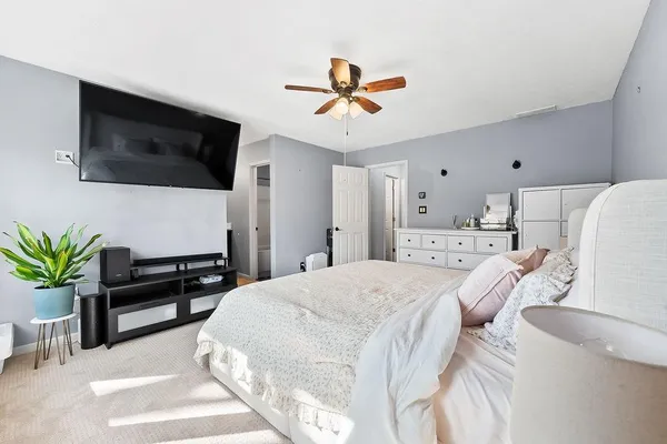 a spacious bedroom with a bed a chandelier and a large window