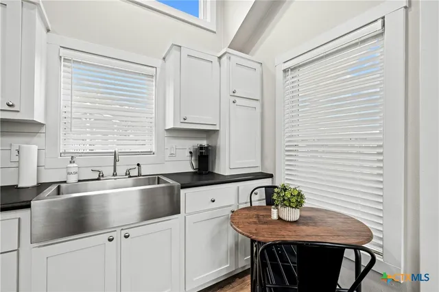 a kitchen with stainless steel appliances granite countertop a sink a stove a dining table and chairs