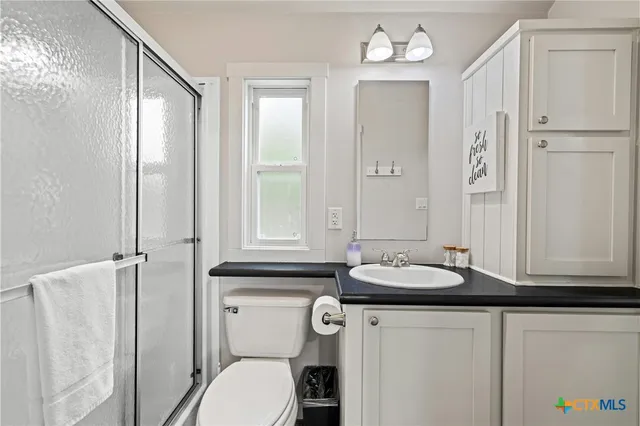 a bathroom with a granite countertop sink vanity mirror and toilet