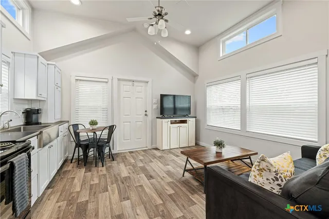 a kitchen with granite countertop a stove a sink dishwasher a dining table and chairs with wooden floor