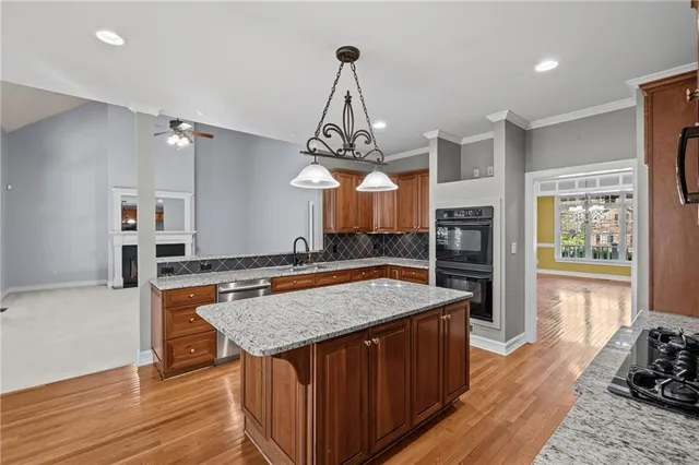 a kitchen with stainless steel appliances granite countertop a kitchen island a stove and a wooden floors