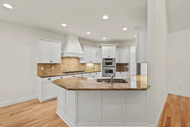 a kitchen with stainless steel appliances granite countertop a stove and white cabinets