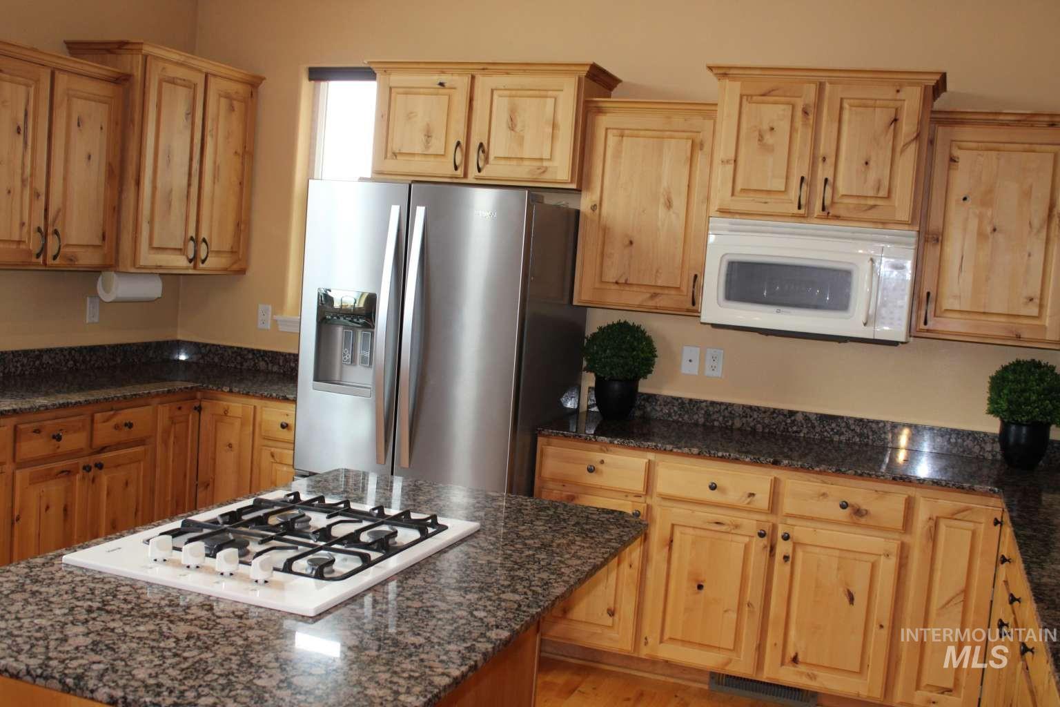 1422 River View Lane Buhl, ID 83316 - Photo 11 of 43 Kitchen featuring white appliances, dark stone counters, a center island, light wood finish cabinets, and light wood-style floors