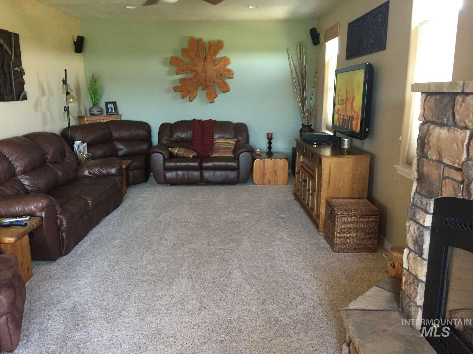 1422 River View Lane Buhl, ID 83316 - Photo 21 of 43 Living room featuring a stone fireplace, light colored carpet, and a ceiling fan
