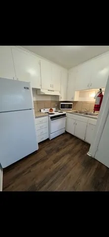 a kitchen with cabinets and wooden floor