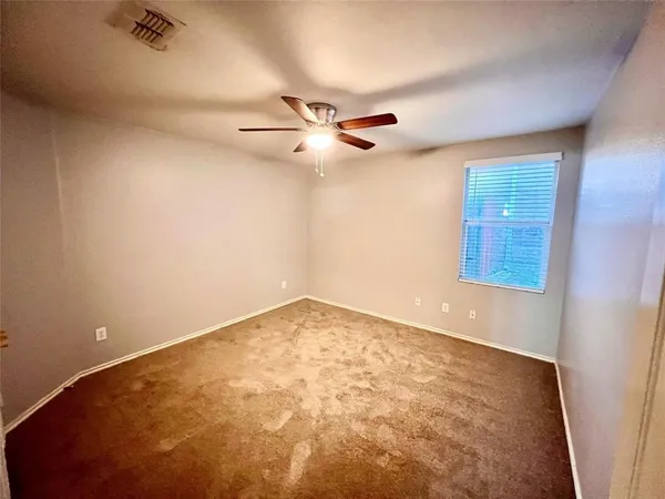 an empty room with ceiling fan and window
