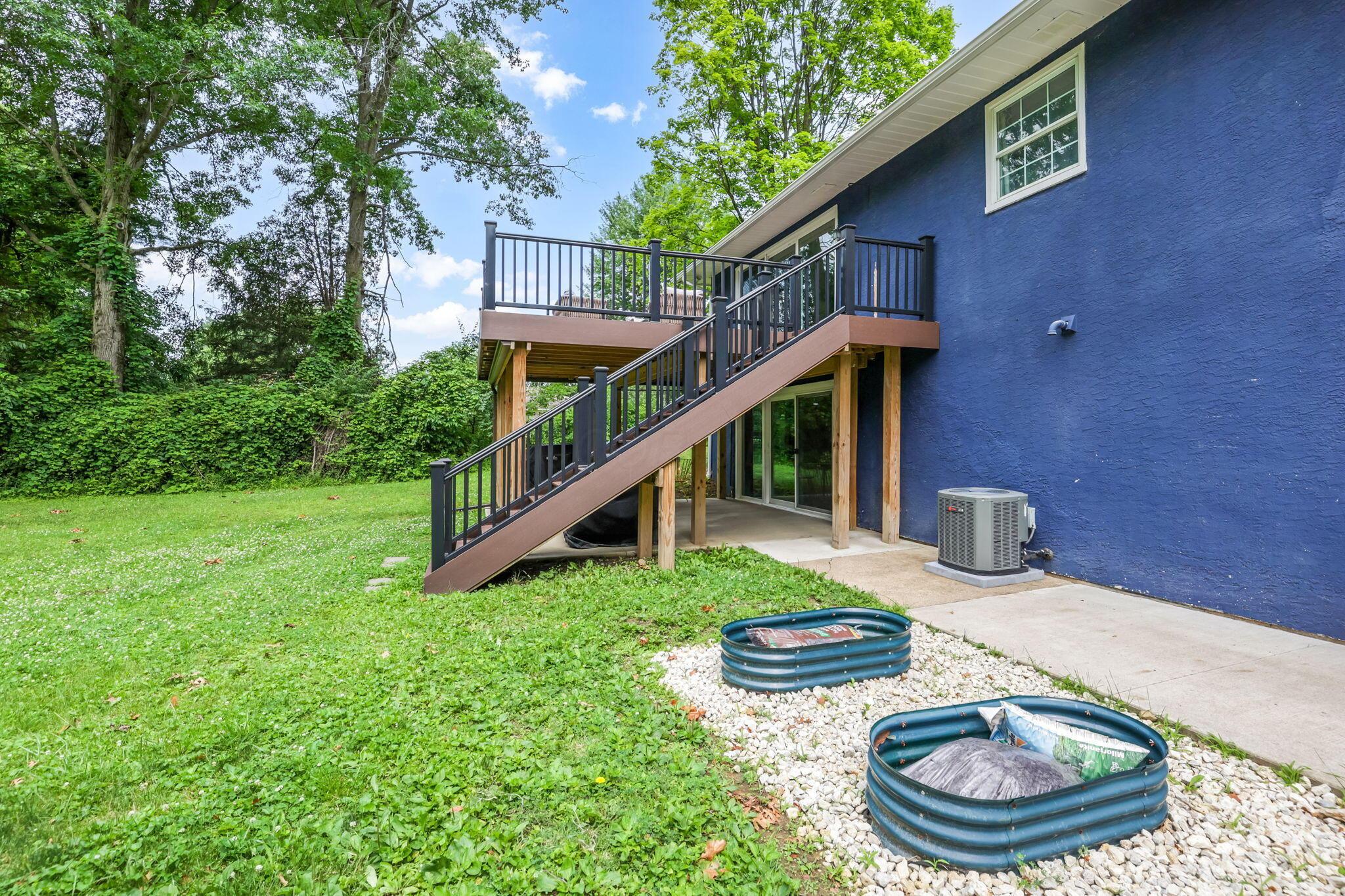14823 Cleveland Road Southwest Pataskala, OH 43062 - Photo 34 of 57 Spacious backyard featuring a two-story deck with dark railings, a stucco exterior, and mature trees providing natural screening