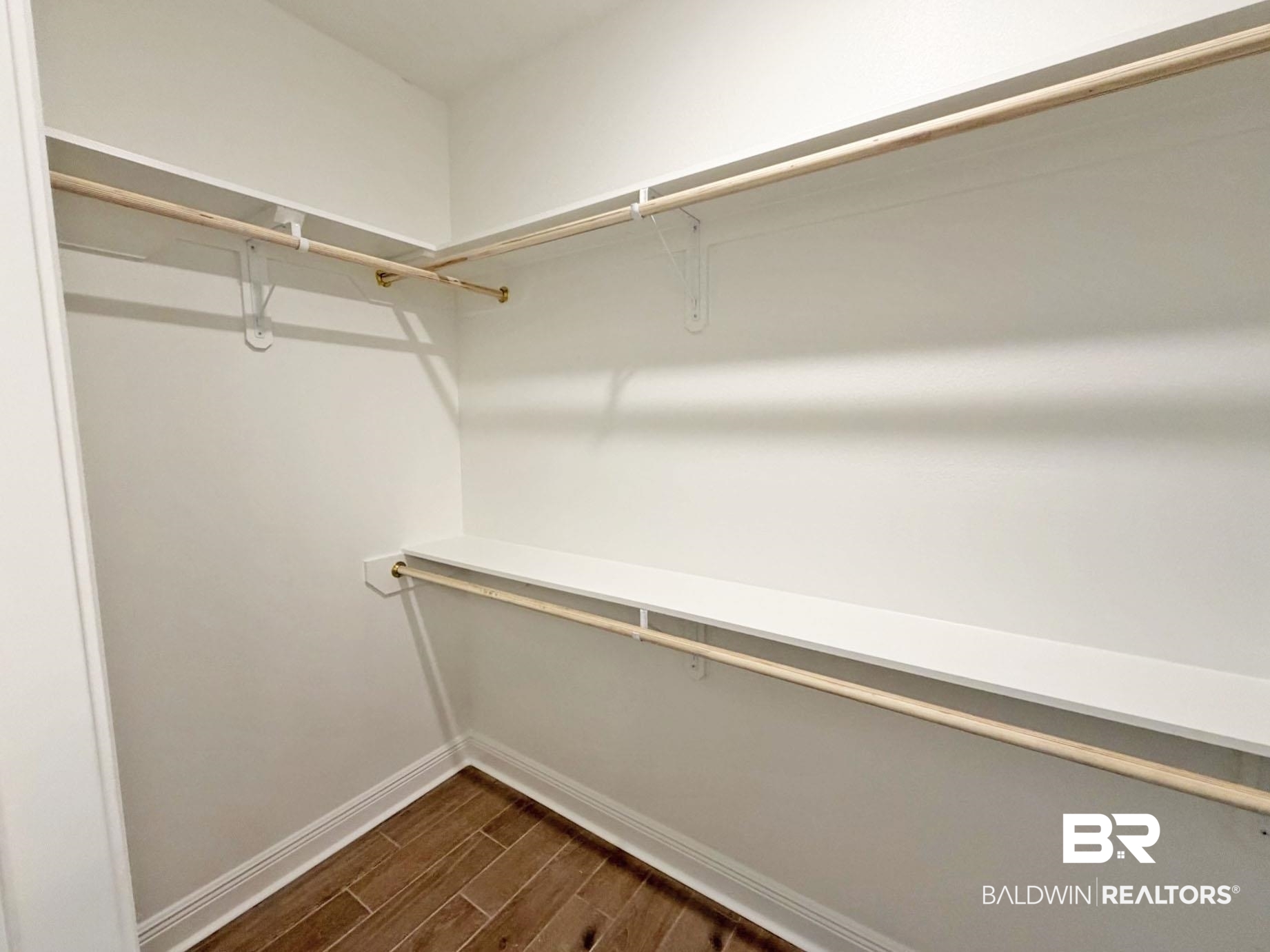 1753 Breckinridge Place Foley, AL 36535 - Photo 14 of 24 Walk-in closet featuring wood-finish flooring, white walls, white baseboards, and built-in shelving with hanging rods
