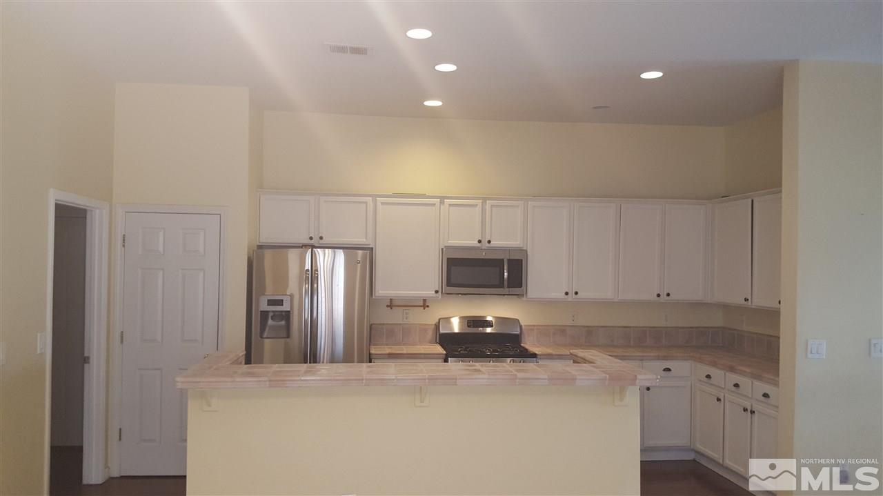 10281 Wolf Ridge Way Reno, NV 89521 - Photo 2 of 22 a kitchen with granite countertop a refrigerator and a stove top oven